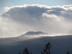 snow blowing from the closer hills